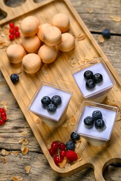 Beautiful shot of white and purple mousse with blueberries and macaroons on a wooden board