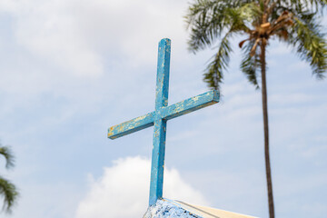 Uma cruz azul com o céu azul ao fundo.