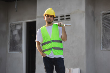 Asian male construction worker holding a shovel at job site