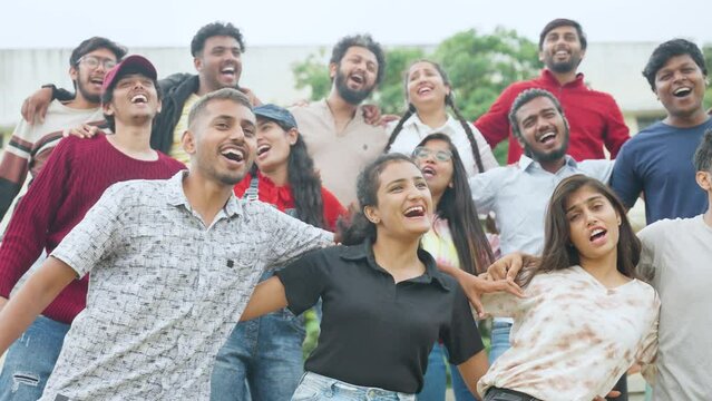 group of friends with hands eachother shoulders dancing while watching sports at cricket stadium - concept of happiness, togetherness and carefree lifestyle