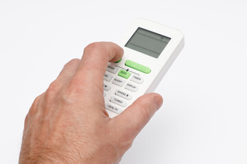 Man's hand using remote controler. Hand holding remote and adjusting temperature of air conditioner mounted on a white wall.