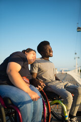 Naklejka premium Tender multicultural couple spending day together. African American man and Caucasian woman in wheelchairs, holding hands. Love, affection, happiness concept