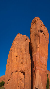Two tall towers of red rock formation and eroded rock walls along the Church Rock Trails in Red Rock Park in Gallup, McKinley County, New Mexico, USA