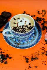 Tuinposter Vertical shot of a Cappuccino with art on an orange table with cookies © Ssayeed Bin Mohiuddin/Wirestock Creators