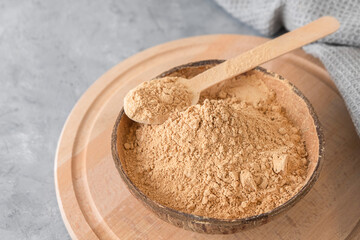 Dietary supplement - maca root powder in a bowl on neutral grey background with copy space.
