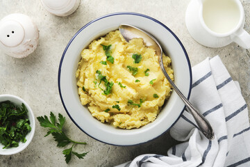 Mashed potatoes. Hot mashed potatoes with butter, fresh parsley herbs and pepper in bowl on slate, stone or concrete backgrounds. Delicious creamy mashed potatoes. Top view.