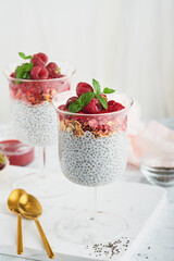 Chia pudding. Healthy vanilla chia pudding in glass with fresh raspberries and mint on white background. Vegan healthy breakfast.