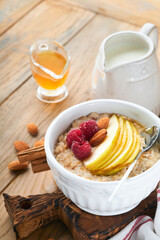 Oatmeal. Bowl of oatmeal porridge with raspberry, pear and honey on old wooden table background. Hot and healthy food for Breakfast, top view, flat lay