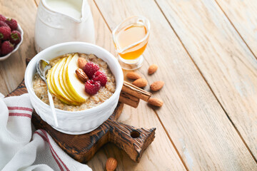 Oatmeal. Bowl of oatmeal porridge with raspberry, pear and honey on old wooden table background. Hot and healthy food for Breakfast, top view, flat lay