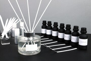 aroma reed diffuser bottle is on black table with essential oil ,frangrance oil bottle and blotter...