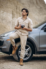 Handsome man travelling by his car and making photos on his camera