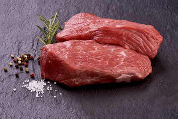 Raw meat, beef steak on black slate plate isolated on white background.