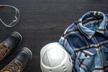 Electrician work uniform items on a wooden background, top view.