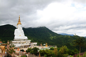 Big white monk statue with green mountain, sky and white cloud background with copy space at Thai temple Phetchabun, Thailand. Landmarks and famous place for travel. Religion and Art of sculpture.