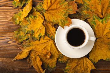 Autumn.Autumn leaves and a hot cup of coffee on a wooden table. Seasonal, morning coffee, Sunday relaxing and still life concept.Flat lay autumn composition.Autumn weekend mood concept.