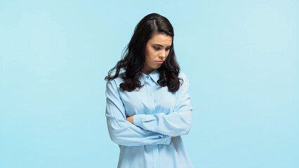 sad young woman in shirt standing with crossed arms isolated on blue