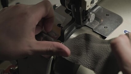 Leather crafting. Closeup of man using professional industrial sewing leather processing machine while making leather craft hand made products in workshop