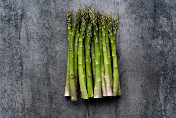 Green fresh raw asparagus on concrete background.Bunch of fresh asparagus top view on gray concrete background