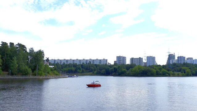 A red boat sails down the river in the summer.
