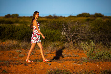 a long-haired girl in a white dress lost in the middle of the Australian desert during sunset, a bush walk in western australia's cape range national park