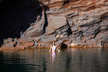 a long-haired girl in a white bikini takes a refreshing dip in a rock pool in karijini national...