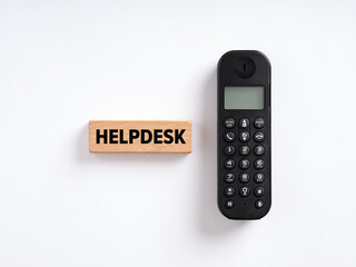 The word helpdesk on wooden block with a wireless phone. Online support service, assistance or help concept.