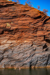a long-haired girl in a white bikini takes a refreshing dip in a rock pool in karijini national park in western australia, an oasis in the middle of the desert in the australian outback
