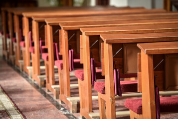 Obraz na płótnie Canvas Detail with wooden prayer benches in a row inside a catholic church