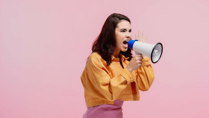brunette woman screaming while making announcement in loudspeaker isolated on pink