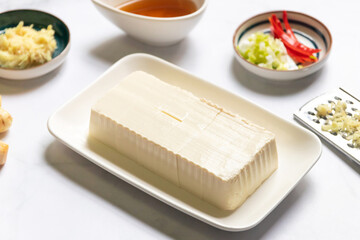 Vegan silken tofu is served hot or cold with a savory soy sauce flavored with green onions, grated ginger and sesame oil.