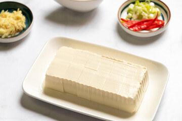 Vegan silken tofu is served hot or cold with a savory soy sauce flavored with green onions, grated ginger and sesame oil.