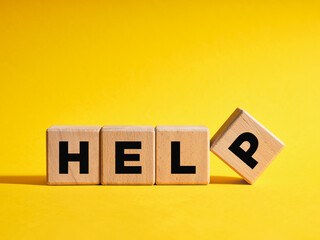 The word Help on wooden cubes with yellow background. Support, assistance or aid concept.