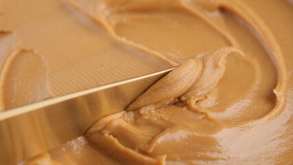 Breakfast with peanut butter. Peanut Butter Spreading with a golden knife, macro shot