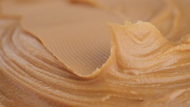 Breakfast with peanut butter. Peanut Butter Spreading with a golden knife, macro shot