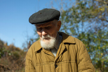 Old man with gray beard and cap. Man of 92 years. Old man in garden.