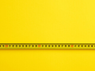 To evaluate or measure the size concept. Tape measure on yellow background with copy space.