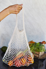 Woman holds eco shopping reusable bag full of fresh vegetables - tomatoes, purple potatoes, eggplants, carrots, sweet pepper. Ecological concern, eco shopping. Vegan eco-friendly lifestyle