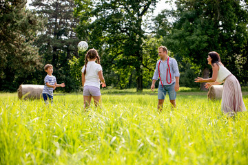 Happy family playing ball in the park on green grass