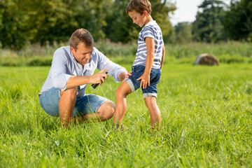 Father applying insect repellent on his son in park