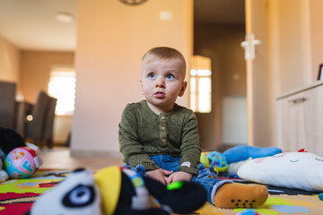 A mother and son are playing on kids carpet with toys baby is playing and sitting on the ground with toys