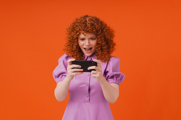 White ginger woman with curly hair playing game on cellphone