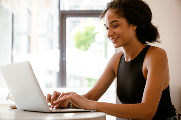 Brunette young woman working with laptop while sitting in cafe