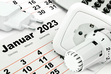 Deutscher Kalender Januar 2023 mit Steckdose, Rechner und Heizungsthermostat  im Winter - obrazy, fototapety, plakaty