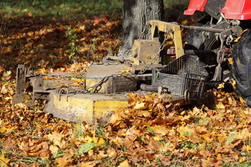Lawn mover machine tractor mowing the grass under yellow foliage in autumn Park 