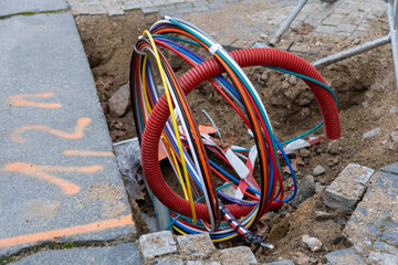 Connecting fiber optic internet connection network cables. Upgrade infrastructure in the city. Construction site with a lot of high speed communication cables buried underground in the street.