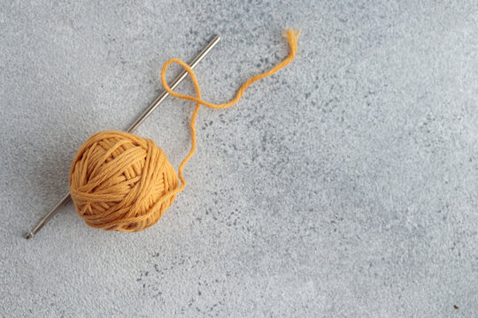 Crochet hook and a small ball of yellow yarn