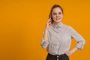 Cute teen girl talking on a mobile phone on a colored background with copy space.