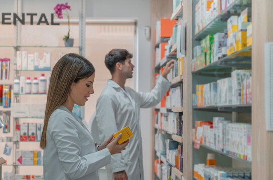 Farmac&eacute;utica y farmac&eacute;utico, colocando productos en la estanter&iacute;a de la farmacia.