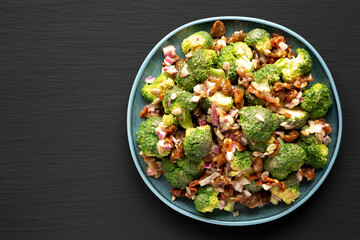 Homemade Broccoli Bacon Salad on a Plate on a black background, top view. Flat lay, overhead, from above. Copy space.