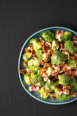 Homemade Broccoli Bacon Salad on a Plate on a black background, top view. Flat lay, overhead, from above. Copy space.